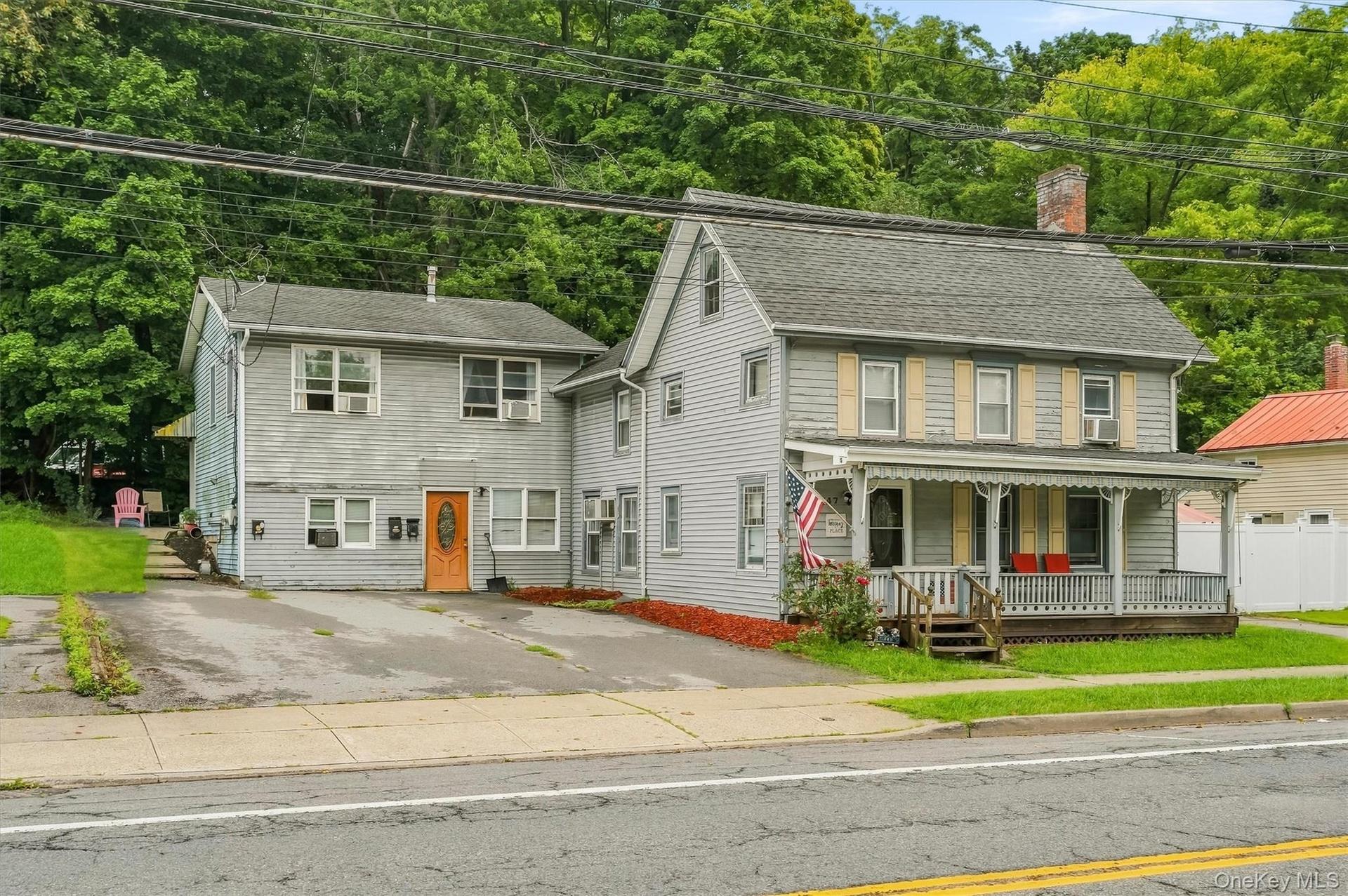Front exterior of 147 Main Street, showing the home’s substantial footprint, driveway and covered front porch.