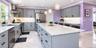 Kitchen featuring stainless steel appliances, an expansive island with seating, pendant lighting fixtures, light-toned countertops.