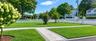 Manicured lawn with a paver walkway, trees, and a white picket fence