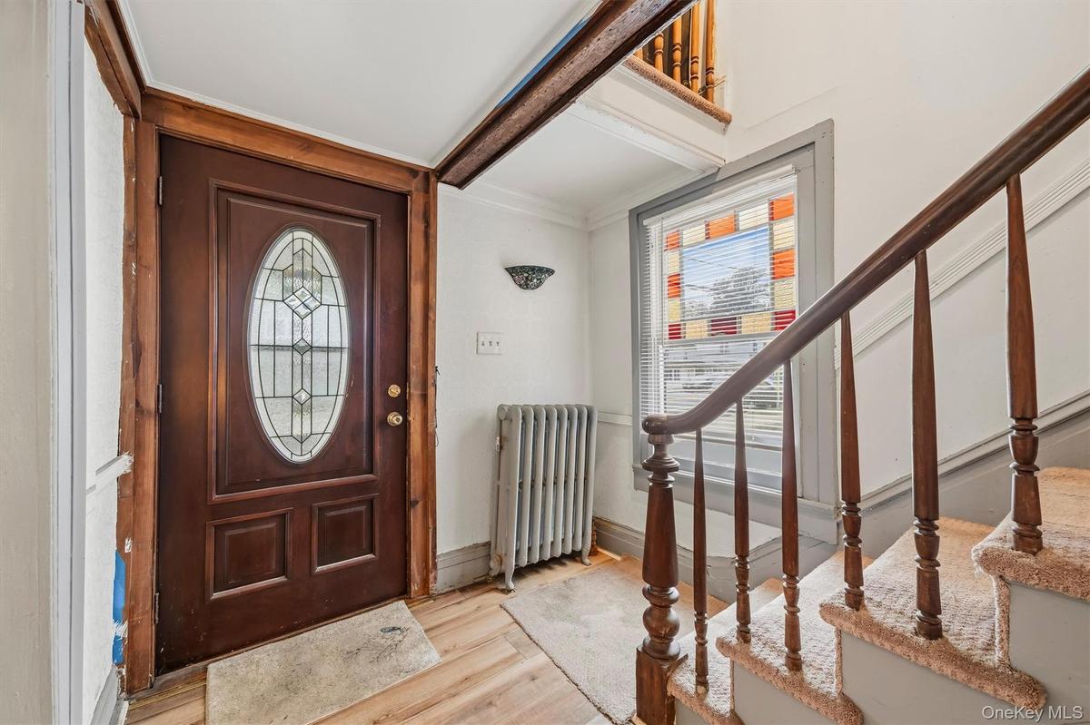 MAIN HOUSE - Front entrance featuring a decorative glass door, original-style woodwork and staircase.