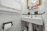MAIN HOUSE - Main-level half bathroom with a pedestal sink and tiled walls.