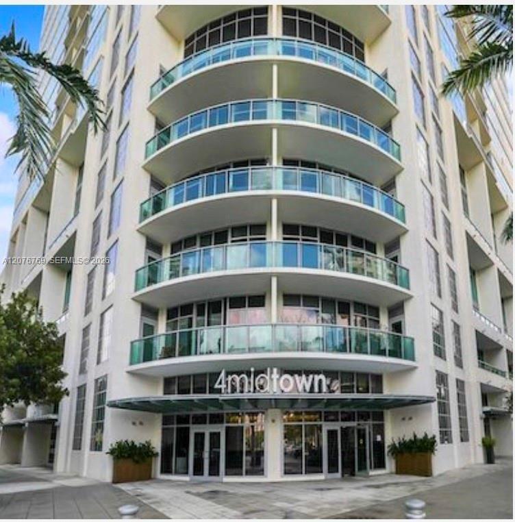 Contemporary building façade featuring rounded glass balconies and street level lobby entrance.