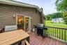 Expansive rear deck with wood-finish flooring, black spindle railing, and sliding glass door access