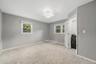 Light gray wall finishes with white trim, two windows, carpet flooring, ceiling-mounted light fixture, and an open closet