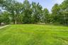 Expansive green lawn framed by mature trees and a rustic wooden fence