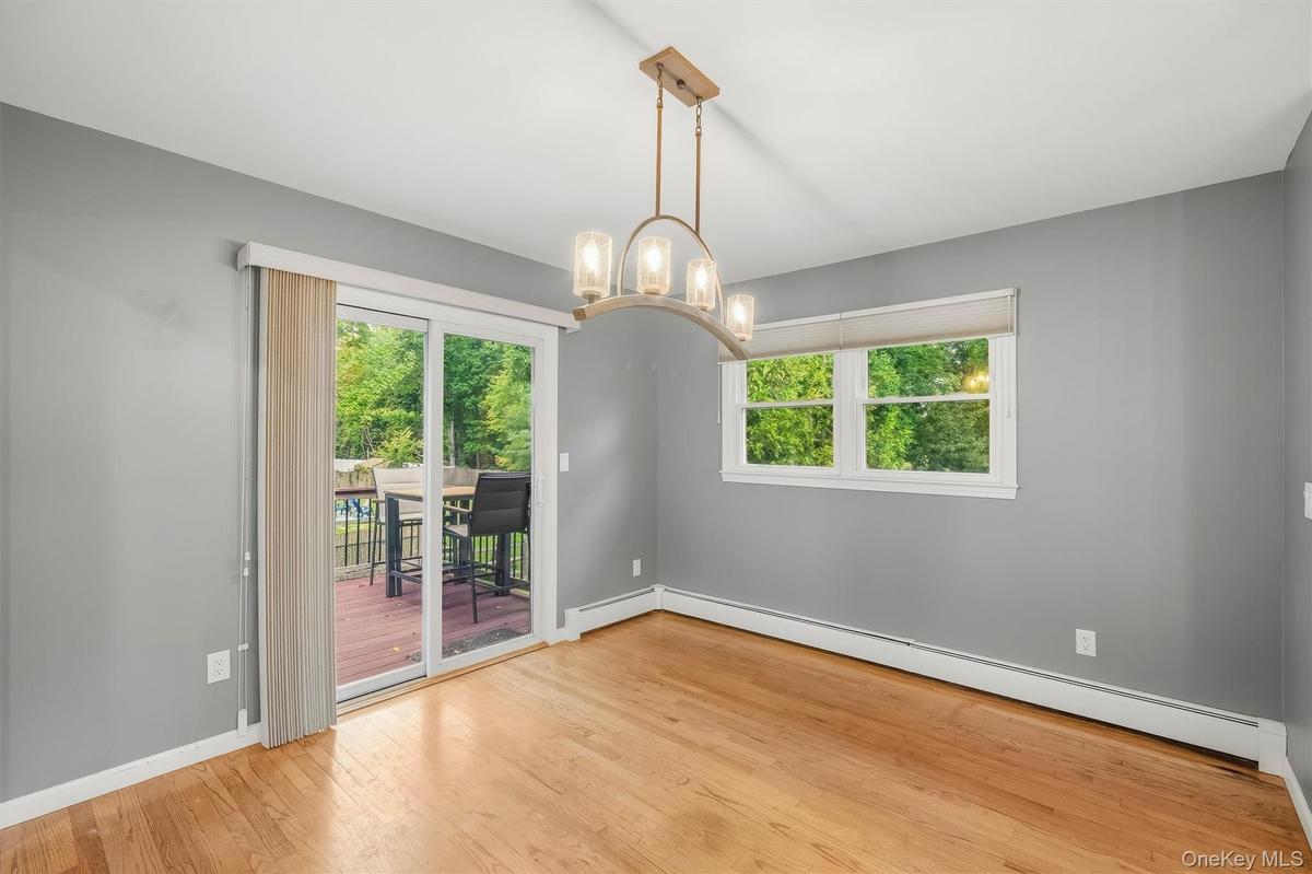 Hardwood flooring, sliding glass door with exterior deck, multiple windows, and a ceiling-mounted light fixture