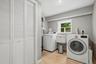 White louvered bifold doors, window with natural light, utility sink, overhead lighting, and wood-finish flooring