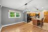 Hardwood flooring, kitchen island with counter seating, wood cabinetry, built-in microwave, and pendant lighting fixtures