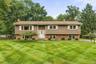 Split-level residence featuring brick and siding facade, contrasting white window shutters, and a white front entry door