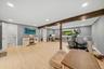 Recessed ceiling lighting, wood-finish flooring, exposed wood beam, large windows, and a separate room with a toilet and towel bar