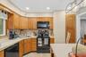 Kitchen featuring wood cabinetry, black appliances, a tile backsplash, and recessed lighting