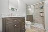 Dark wood vanity with a white marble countertop, brushed nickel faucet, and an arched frameless mirror
