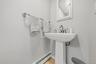 Pedestal sink with a polished chrome faucet, mirrored medicine cabinet, and light-toned wood-finish flooring