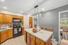 Kitchen featuring wood cabinetry, light-colored countertops, black appliances, and recessed lighting