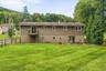 Expansive green lawn with a split-rail fence, rear balcony, and lower-level patio area