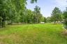 Expansive green lawn with mature trees and perimeter fencing