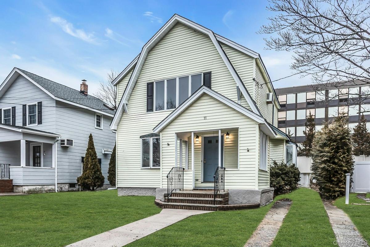 Gable-front home featuring light-colored siding and a blue entry door