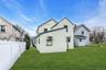 Expansive grassy yard with a white privacy fence
