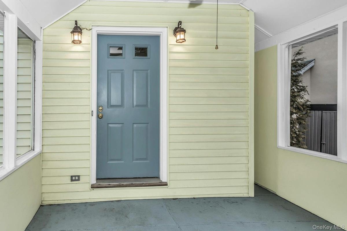 Enclosed porch entry featuring a paneled door with upper glass inserts, two exterior wall lanterns, and a ceiling fan