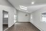 Vaulted ceiling with an integrated skylight, wood-finish flooring, recessed lighting, white baseboards, and sliding glass doors