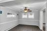 Spacious room featuring wood-finish flooring, light gray walls with white chair rail molding, and a bronze ceiling fan with integrated lighting