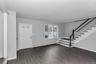 Entryway featuring wood-finish flooring, a contemporary staircase with dark wood-finish handrails and white balusters, and a paneled entry door