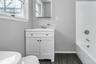 Bathroom featuring a white vanity with integrated sink, chrome faucet, and mirrored medicine cabinet