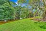 Expansive green lawn with mature trees and natural water feature
