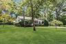 Expansive green lawn with mature trees and established landscaping
