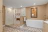 Teak fold down shower seat, frameless glass shower with multiple shower heads,  soaking tub