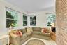 Exposed brick accent wall, multiple windows, crown molding, and tiled flooring
