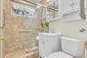 Glass-enclosed shower with full-height tile surround, window, and grab bars