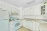 Kitchen featuring white cabinetry, light-toned countertops, tile flooring, a white range, and a white refrigerator