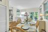 Bright dining area with wood-finish flooring, a glass-top table, and natural light from multiple windows and glass doors