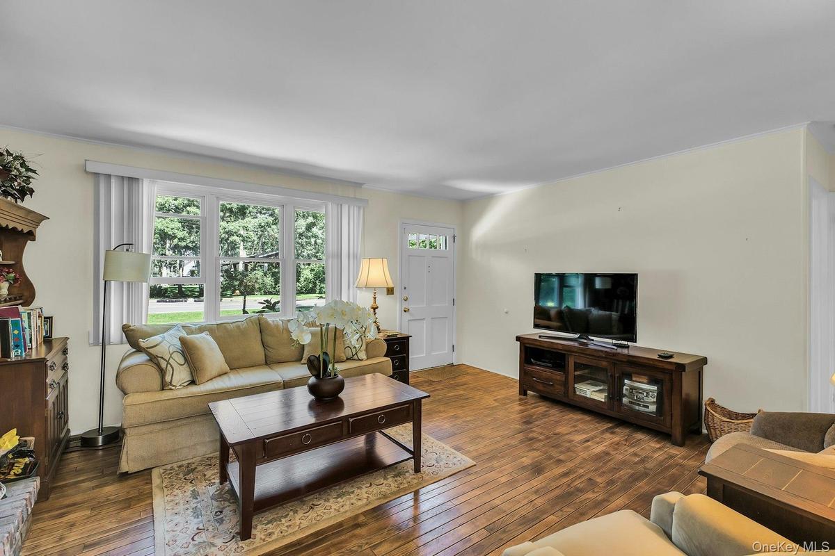 Light-toned wall finishes, wide plank wood-finish flooring, and a multi-pane window