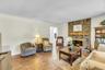 Brick fireplace with a wood mantle, wood-finish flooring, and crown molding