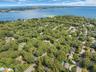 Expansive wooded landscape with winding roads and scattered residential properties, bordered by a large body of water