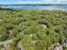 Expansive natural landscape with dense tree coverage, bordered by a body of water with distant shorelines