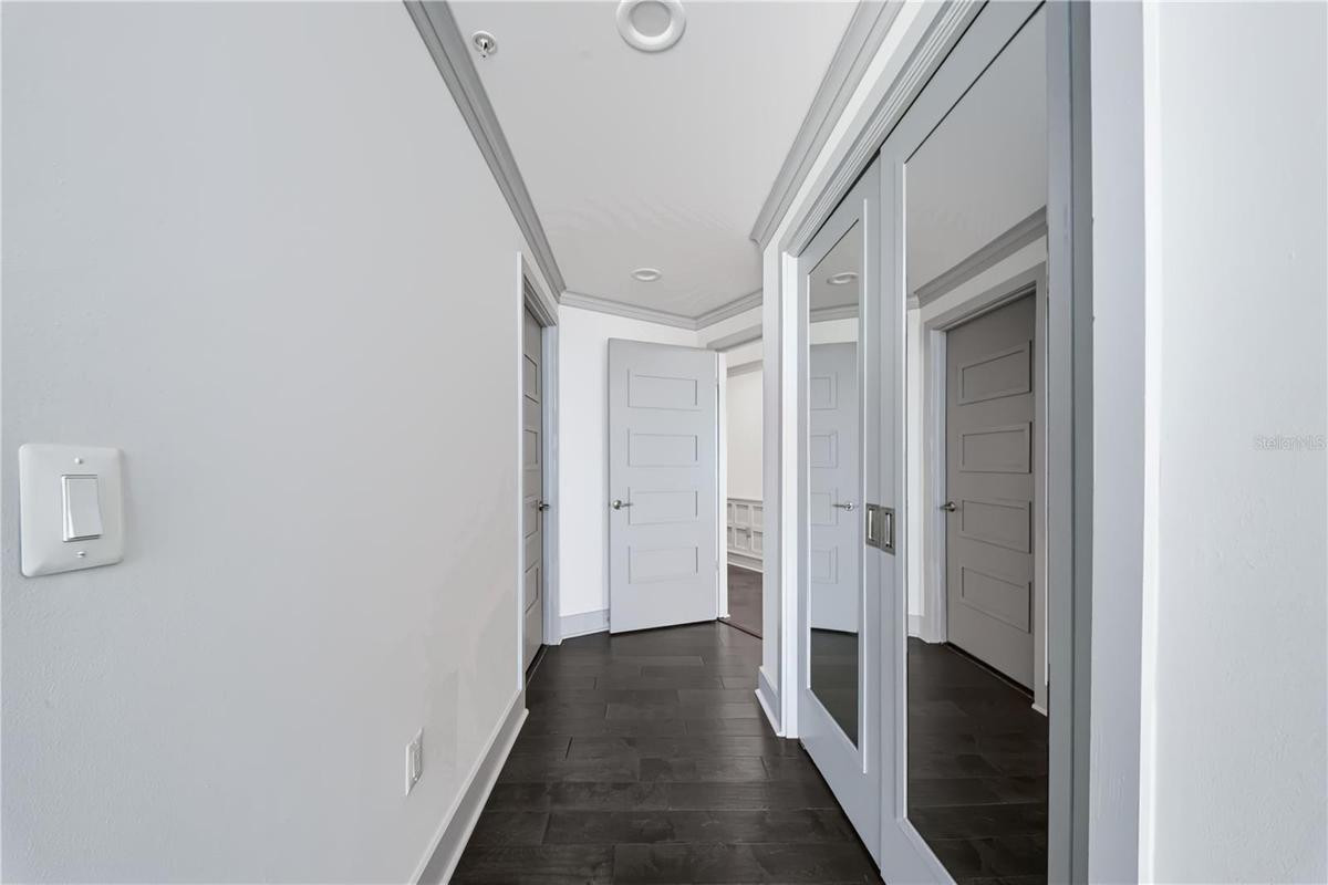 PRIMARY BEDROOM HALL / SECOND CLOSET. Mirror covered double doors has second closet in bedroom hall.