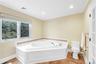 Bathroom with a bath, crown molding, light tile patterned floors, and recessed lighting