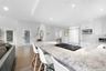 Kitchen featuring light stone countertops, open floor plan, white cabinets, built in appliances, and dark wood-type flooring