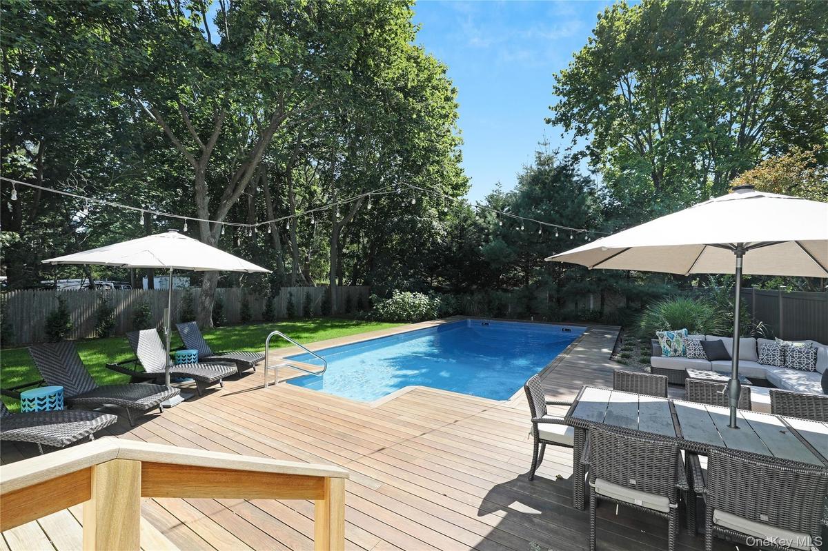 View of swimming pool featuring an outdoor hangout area, a fenced backyard, a wooden deck, view of scattered trees, and a patio area