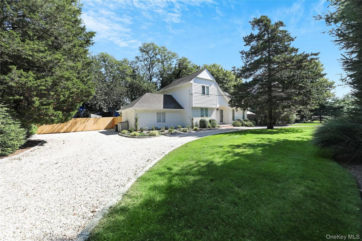 View of front facade featuring driveway and a shingled roof
