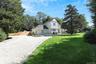 View of front facade featuring driveway and a shingled roof