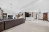 Spacious open-concept room featuring large format tile flooring, recessed lighting, a built-in media cabinet, and a curved staircase with an ornate wr