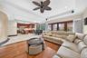 Open-concept living area featuring wood-finish flooring, a tray ceiling with recessed lighting, and a ceiling fan