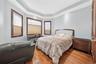 Hardwood flooring, tray ceiling with recessed lighting, multiple windows with wood trim, interior wood door