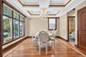 Hardwood flooring with inlay, extensive wood trim, multiple large windows, coffered ceiling, and a crystal chandelier