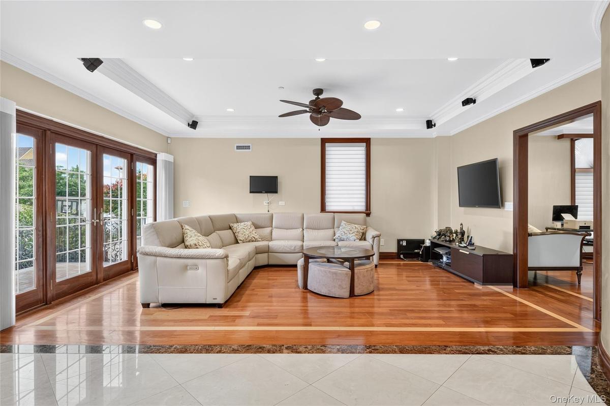 Hardwood flooring with a marble border, recessed lighting, crown molding, double French doors, and a ceiling fan