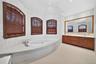 Integrated soaking tub with deck, dual vanities with undermount sinks, large wall mirror, and tiled walls